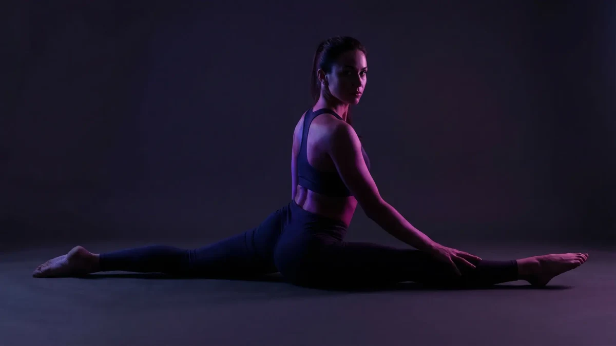Woman performing full splits in a dark studio with purple lighting — Traditional Yoga at UNDRGRND Movement